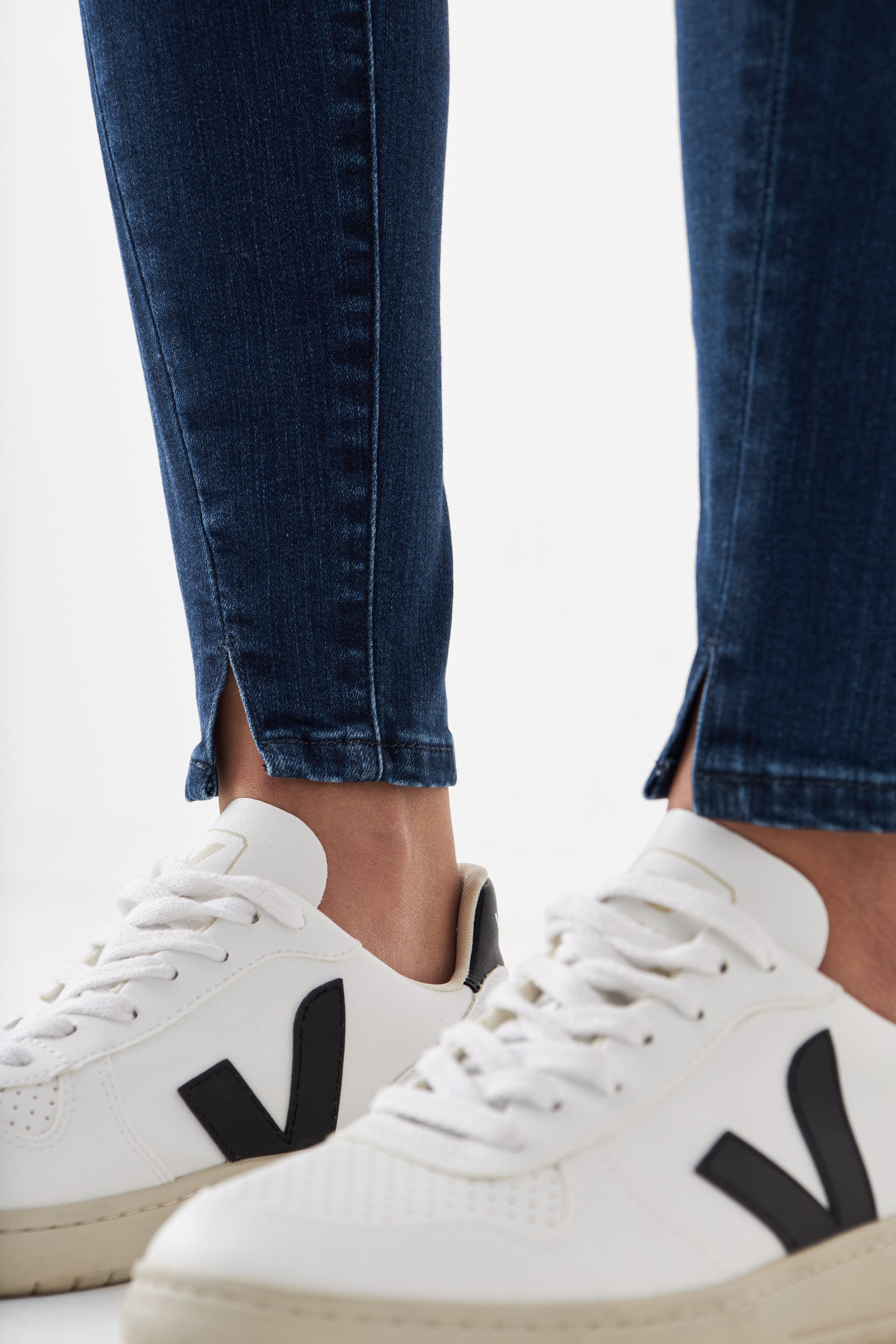 Dunkelblaue SUN UP Skinny Jeans mit schrägen Außennähten und Saumschlitz; eng dank Powerstretch-Passform, getragen zu weißen Sneakern.