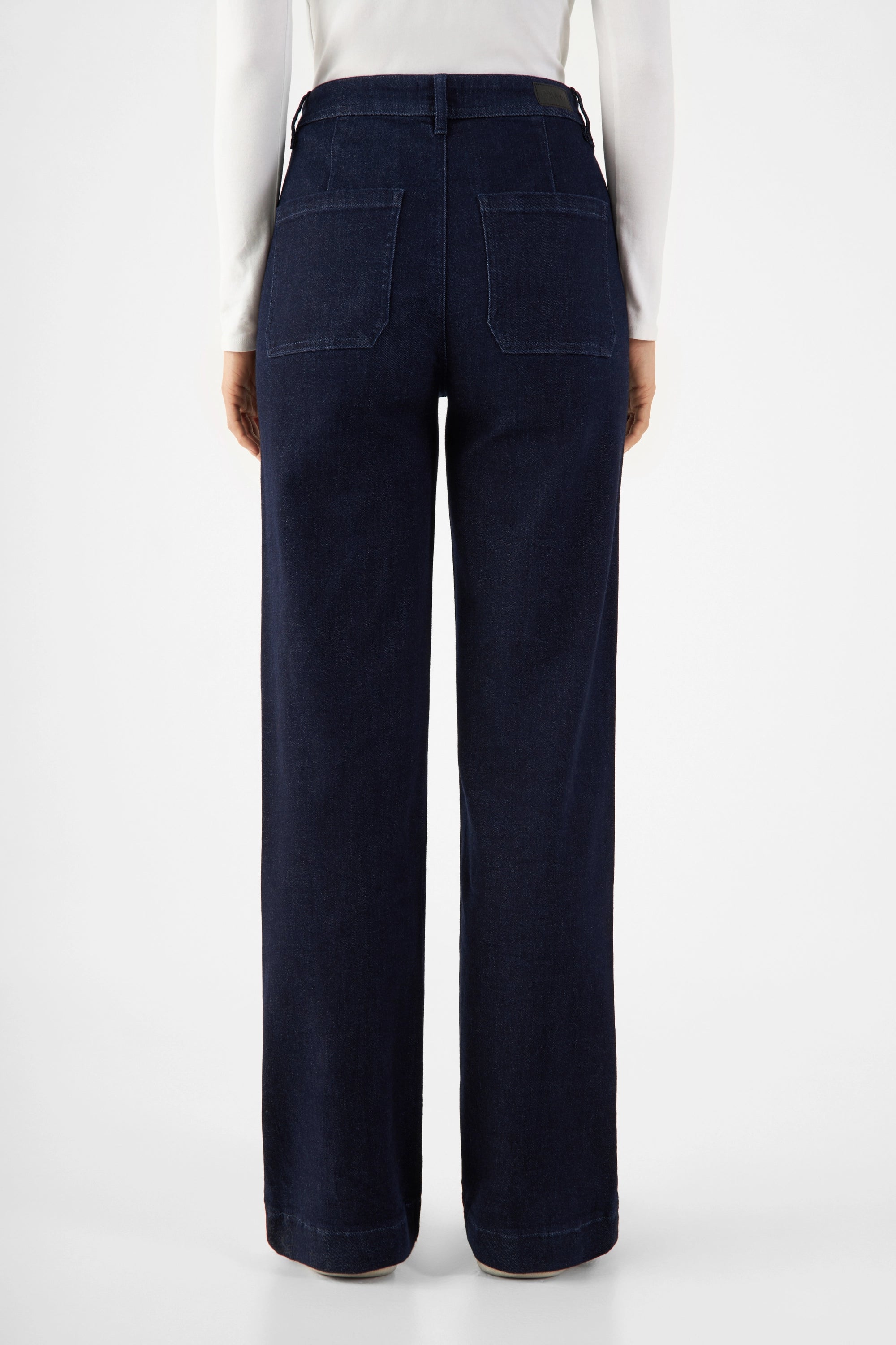 Rückenansicht einer dunklen Raw-Blue-Jeans im DEW Sailor Flared-Fit: hoch tailliert, weiter werdendes Bein, zwei Rückentaschen aus Bio-Denim.