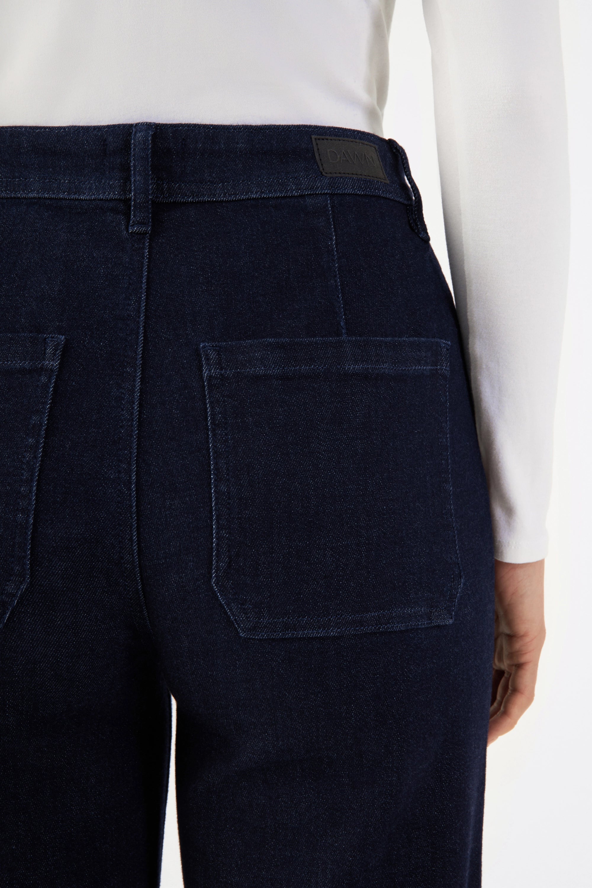Rückansicht der DEW Sailor Raw Blue Jeans in High-Waist, dunklem Bio-Denim, mit zwei hinteren aufgesetzten Taschen und DAWN-Logo am Bund.
