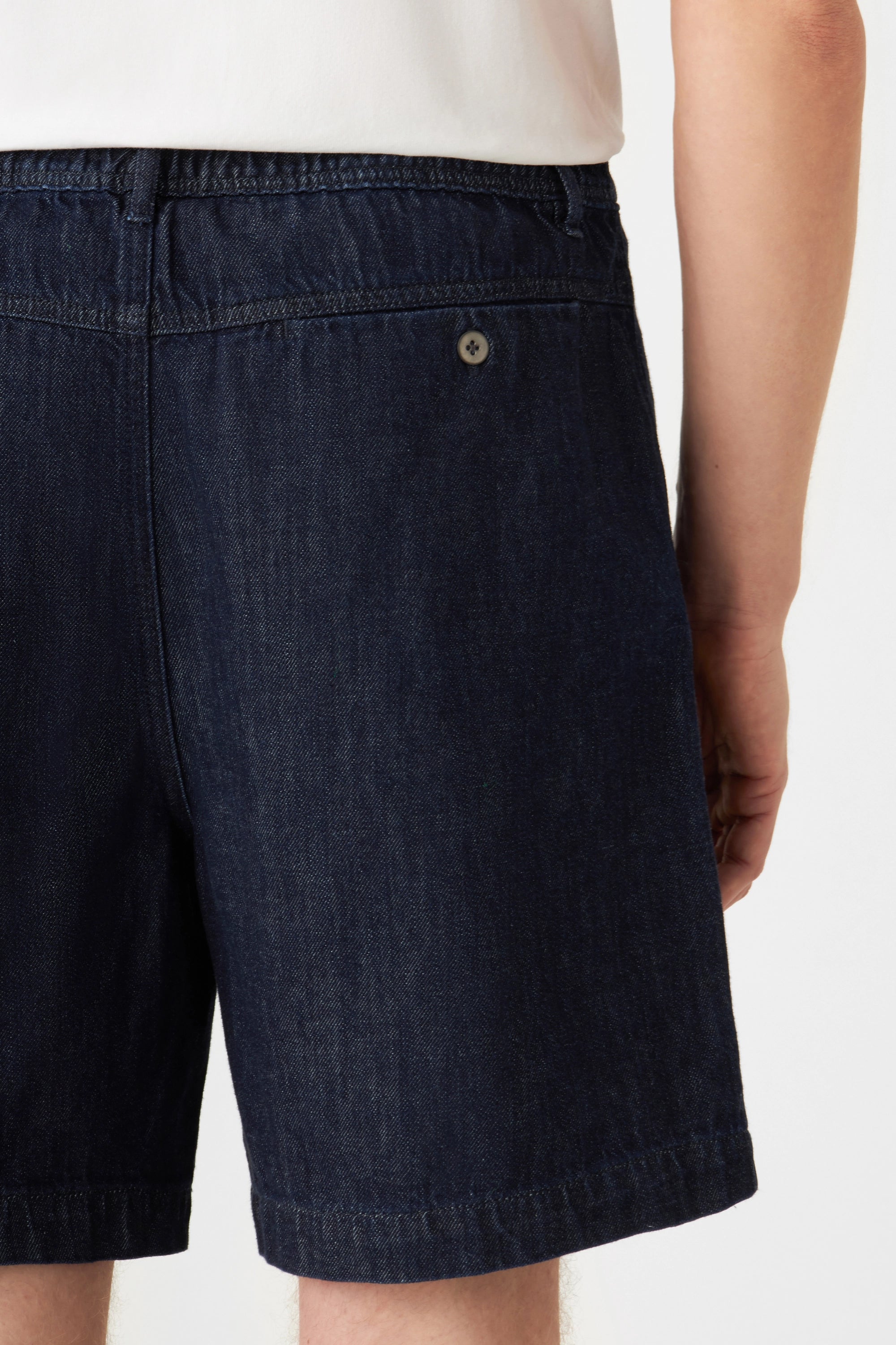 Dunkelblaue SHORTY Lightweight Hemp Shorts in Raw Blue, mittlere Taille, weiter Schnitt; Rückentasche mit Knopfverschluss sichtbar.
