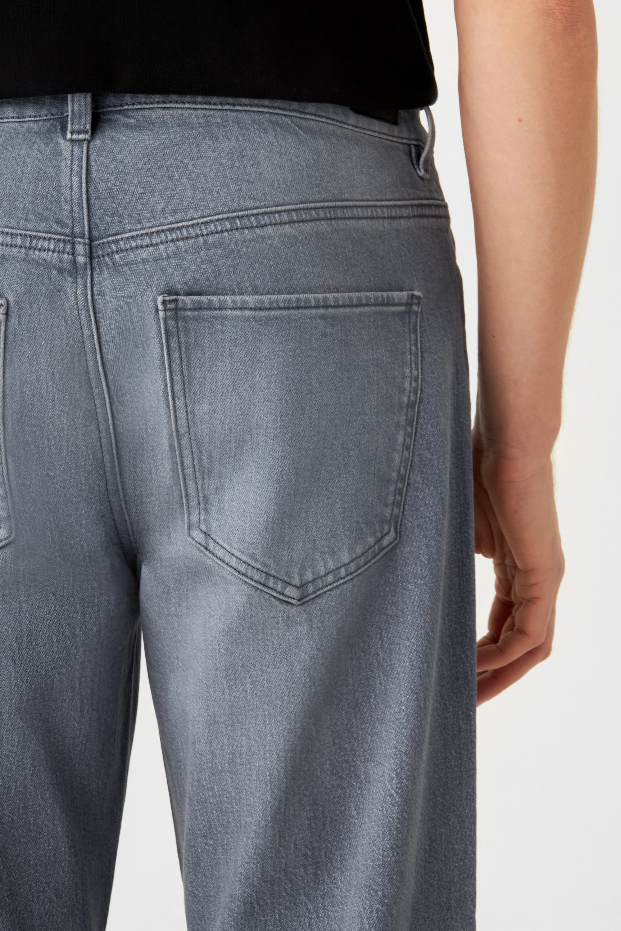Mittelgraue RISE Jeans mit entspannter Passform und schmal zulaufendem Bein; Rückseite mit einer Gesäßtasche und dezenten Nähten.