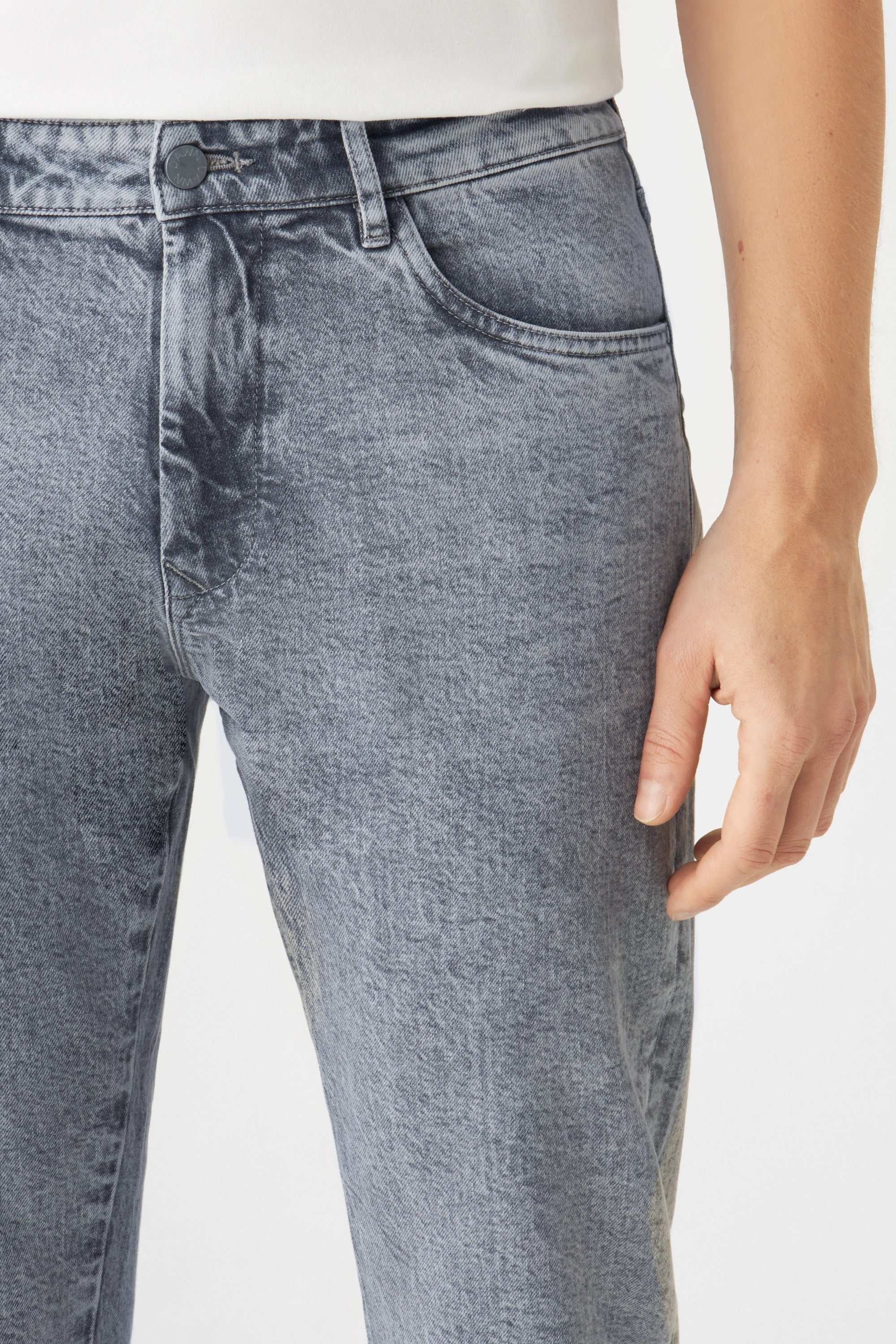 Frontansicht der DUSK Jeans in Special Light Grey: mittlere Taille, gerades Bein, Knopfverschluss, Gürtelschlaufen; Hand am Oberschenkel.