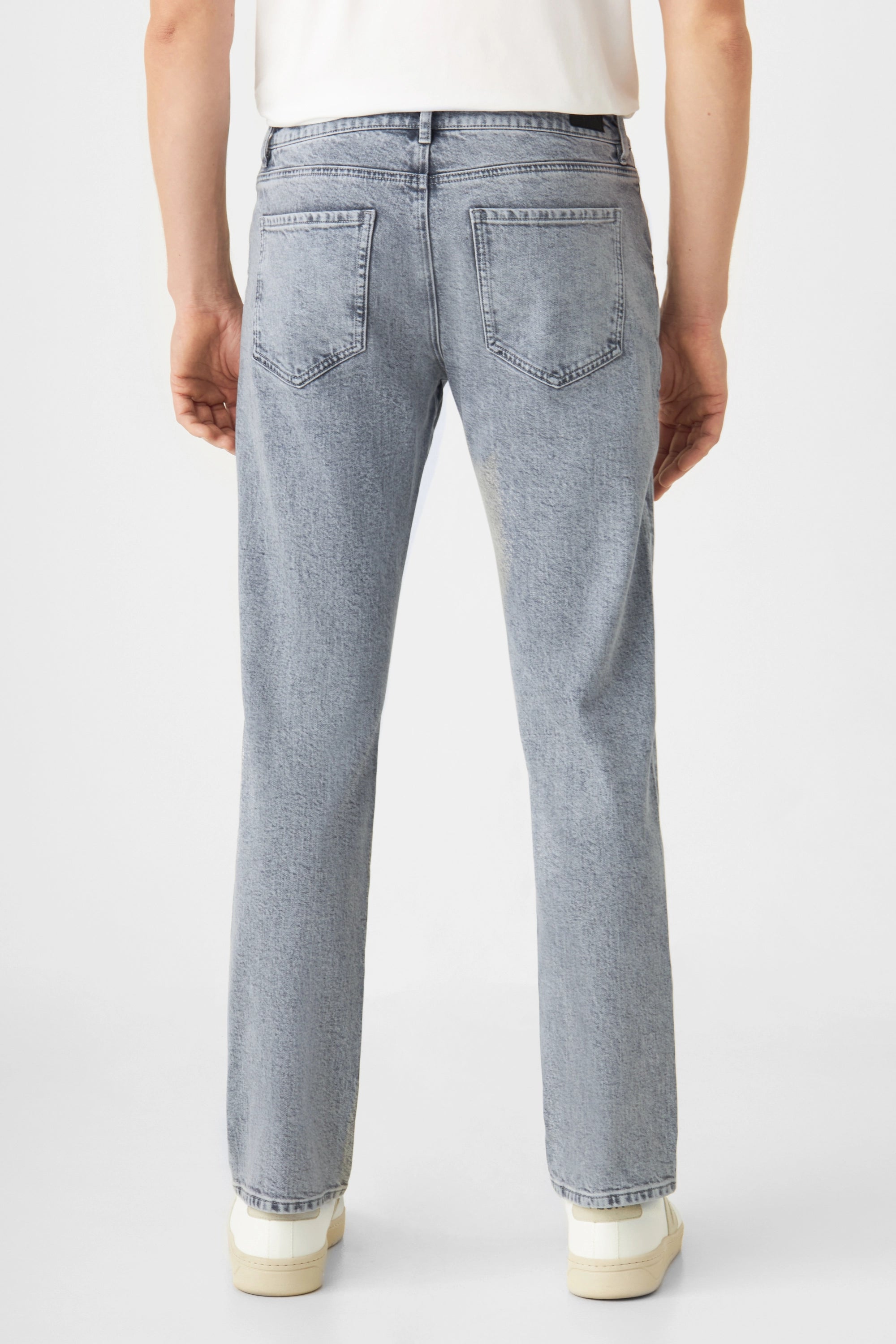 Rückenansicht einer hellgrauen DUSK-Jeans im Regular Slim Fit; zwei Gesäßtaschen, mittlere Taille, gerades Bein, getragen mit weißem Oberteil und Sneakers.