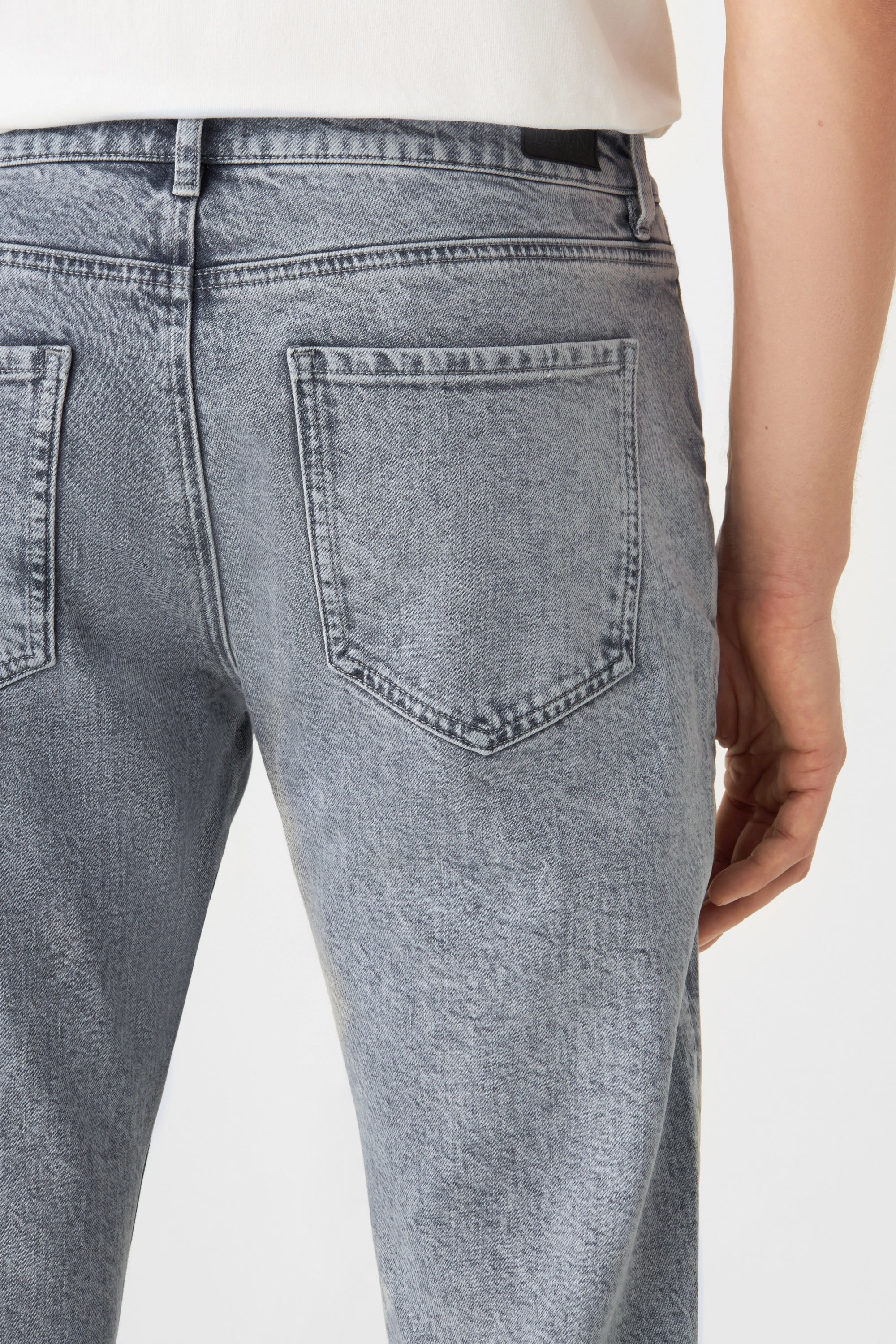 Rückenansicht einer hellgrauen DUSK-Jeans aus Bio-Baumwolle, mit zwei Gesäßtaschen, dezenter Waschung und Bund mit Gürtel-Schlaufen.