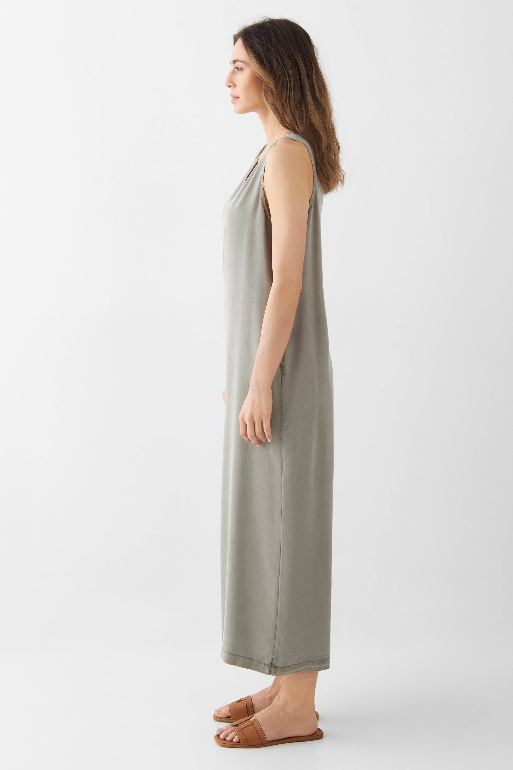 MOONLIGHT Overall in Rock Olive, Seitenansicht einer Frau in ärmellosem Jumpsuit mit V-Ausschnitt, lockerweite Beine, Sandalen.