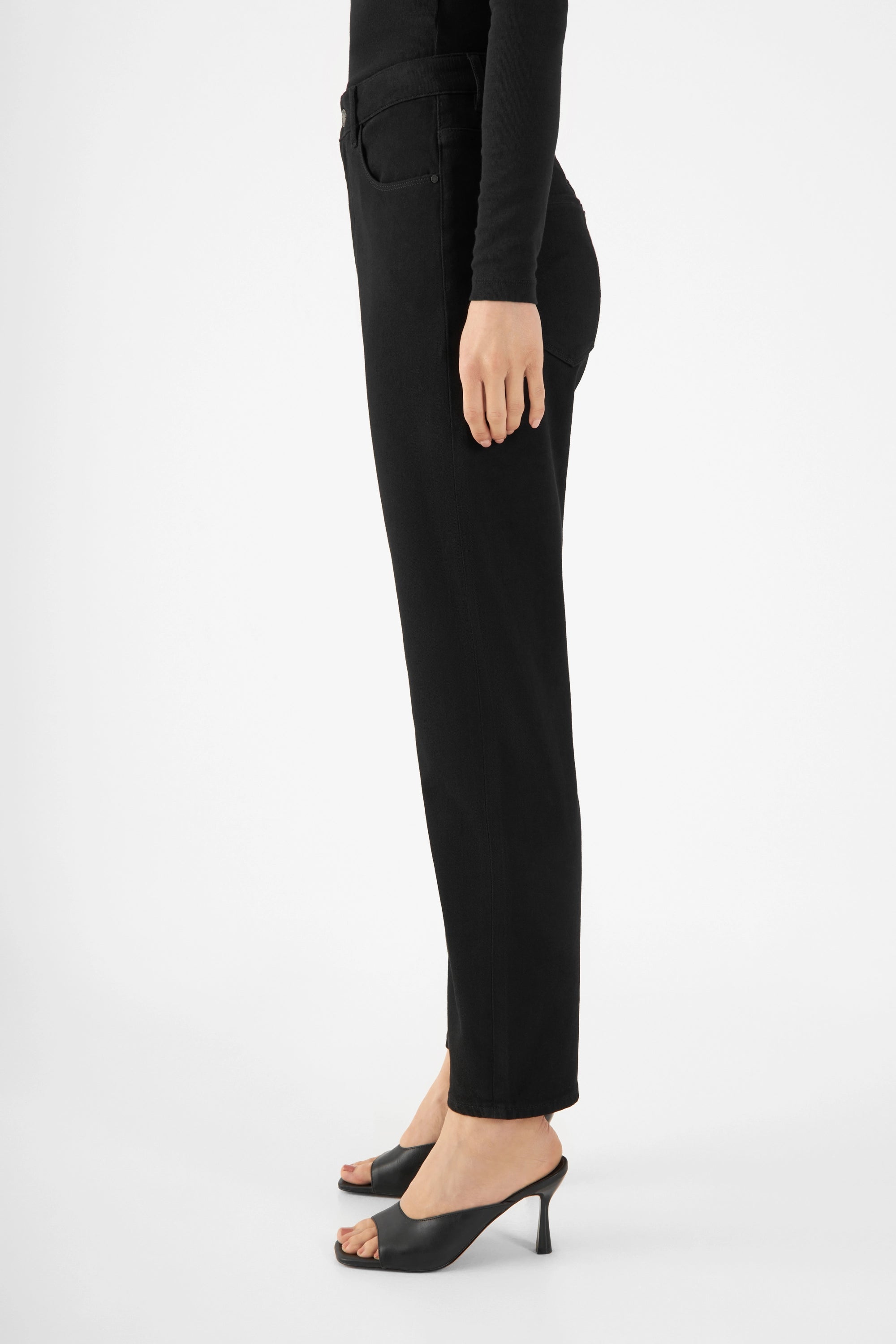 Schwarze STARDUST O-Shape Jeans Stay Black, Seitenansicht: hohe Taille, entspannte Hüfte, mittlerer Beinverlauf, Saum zum Abschluss schmal; getragen mit schwarzen High-Heels.